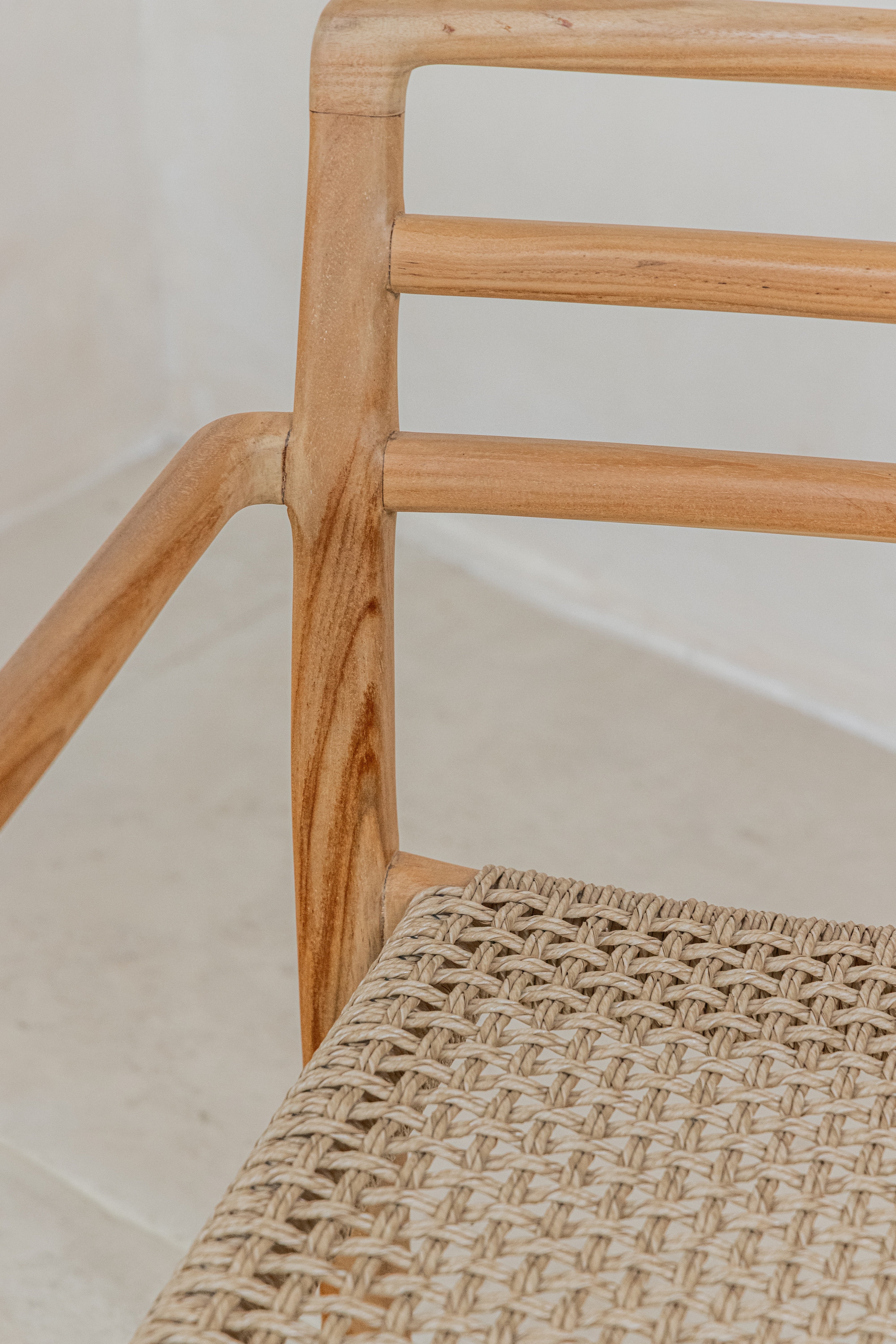 Stackable teak outdoor dining chair with a woven wicker seat detail