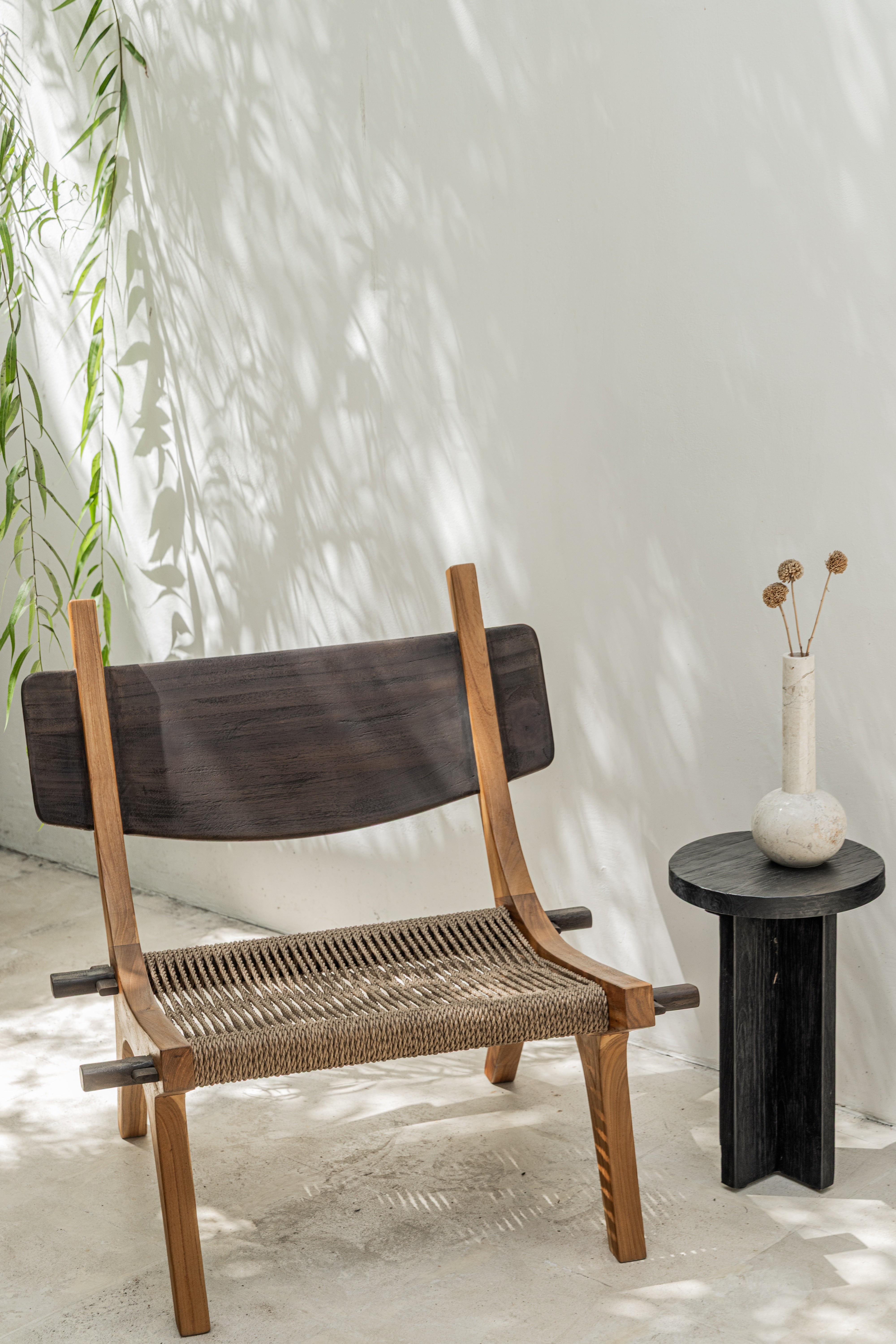 Spanish inspired teak lounge chair with woven rope seat in outdoor setting