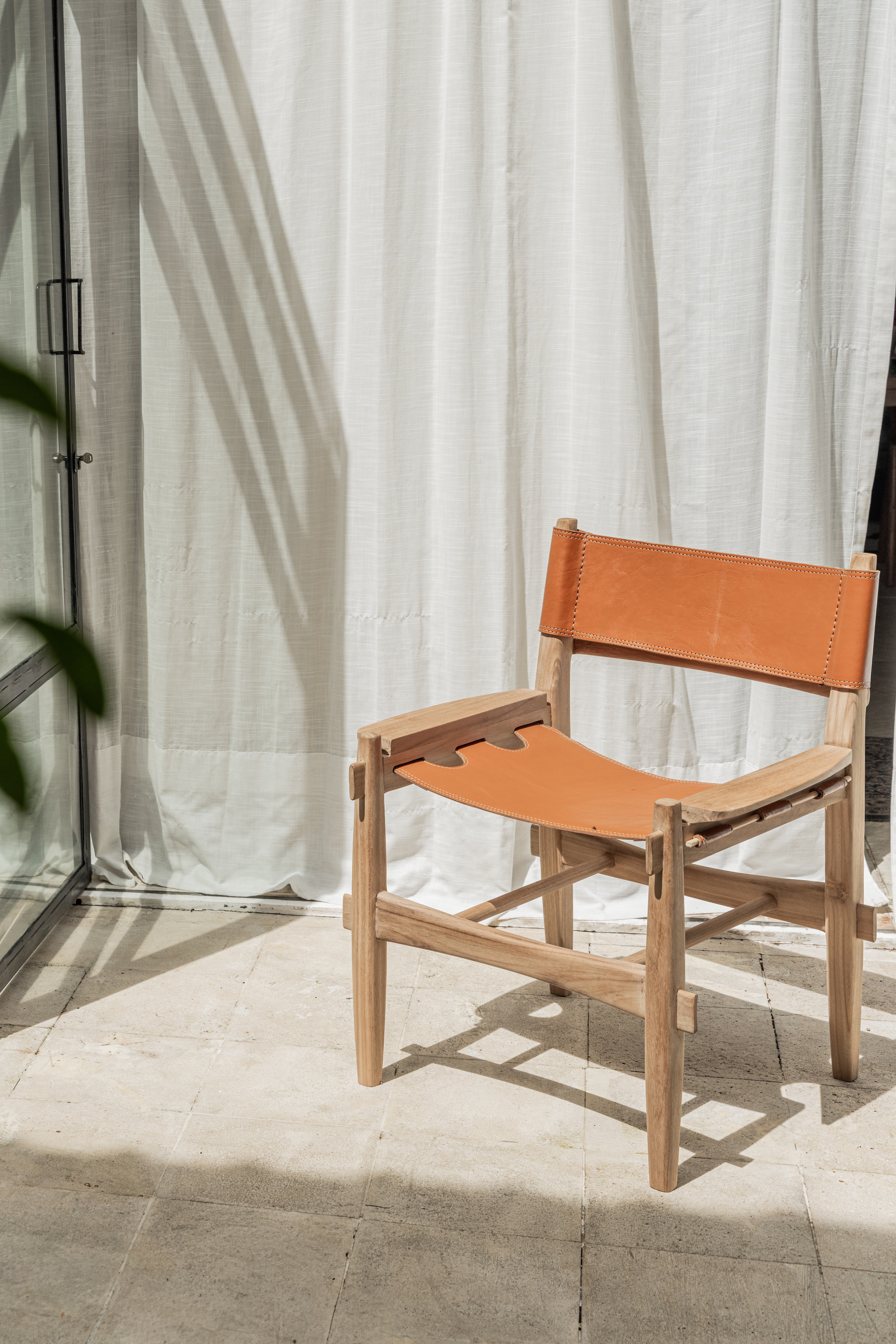 Tan top grain leather sling dining chair on a solid teak frame
