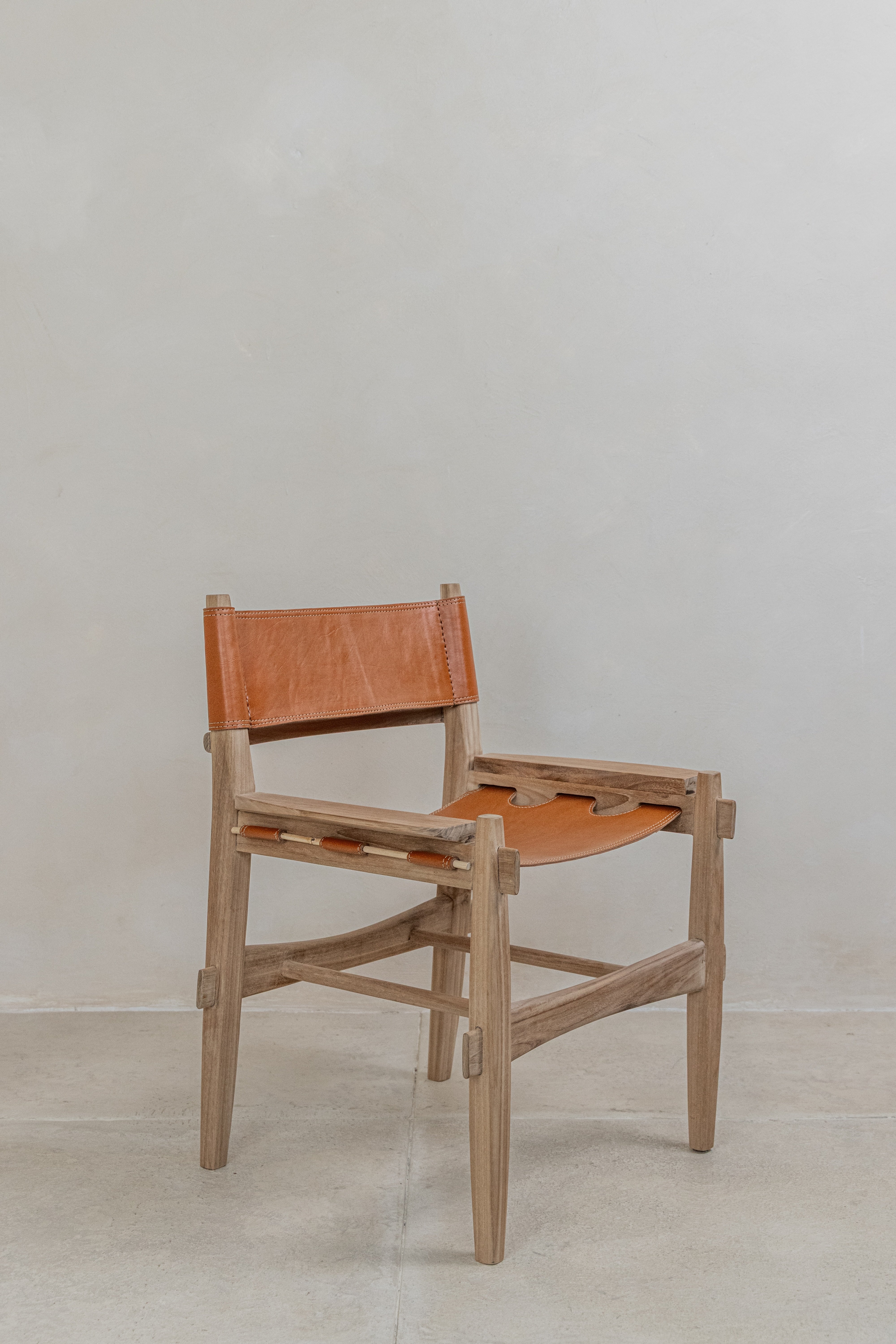Tan top grain leather sling dining chair on a solid teak frame front angle shot