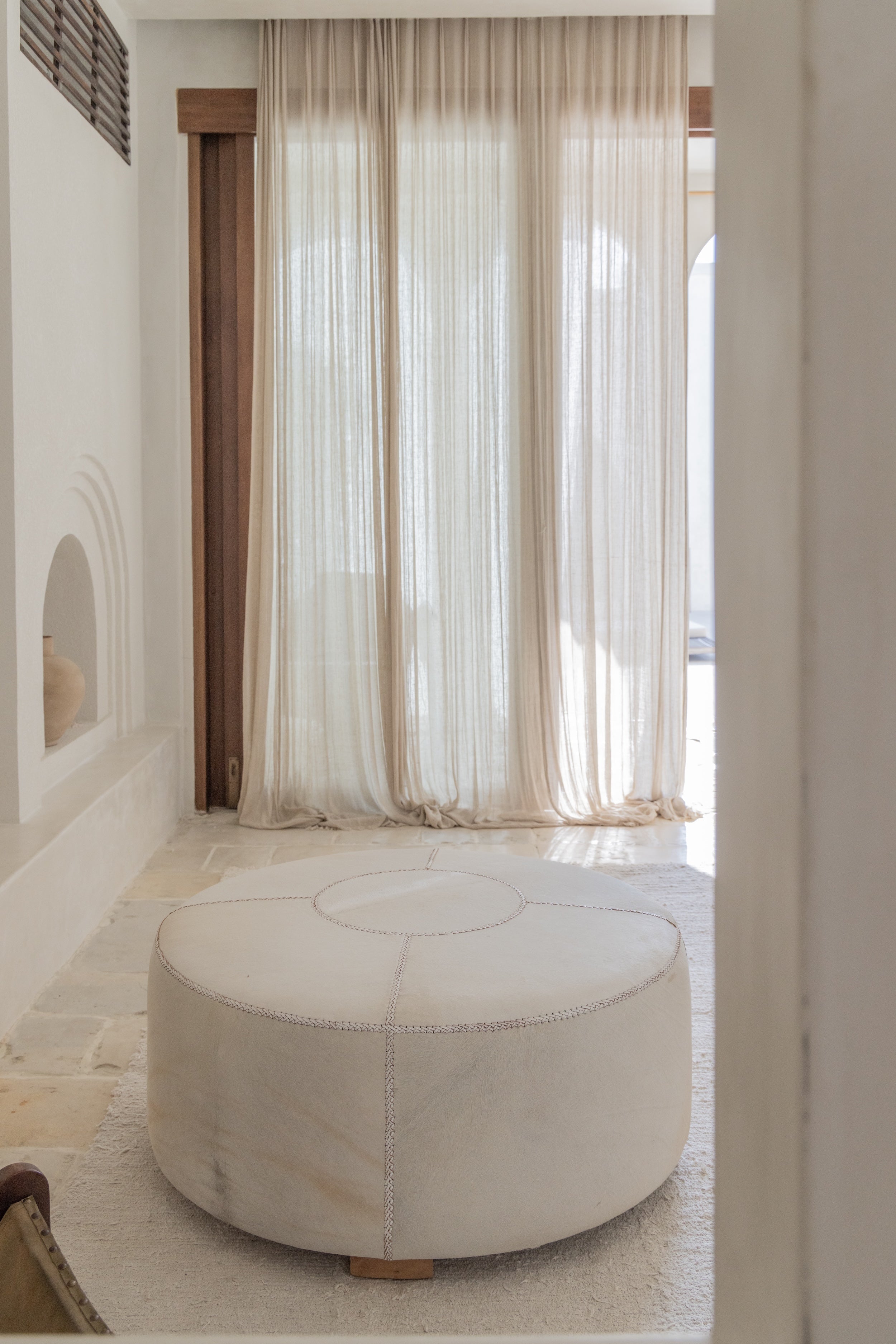 leather ottoman made from cowhide leather, white, show in room with curtains